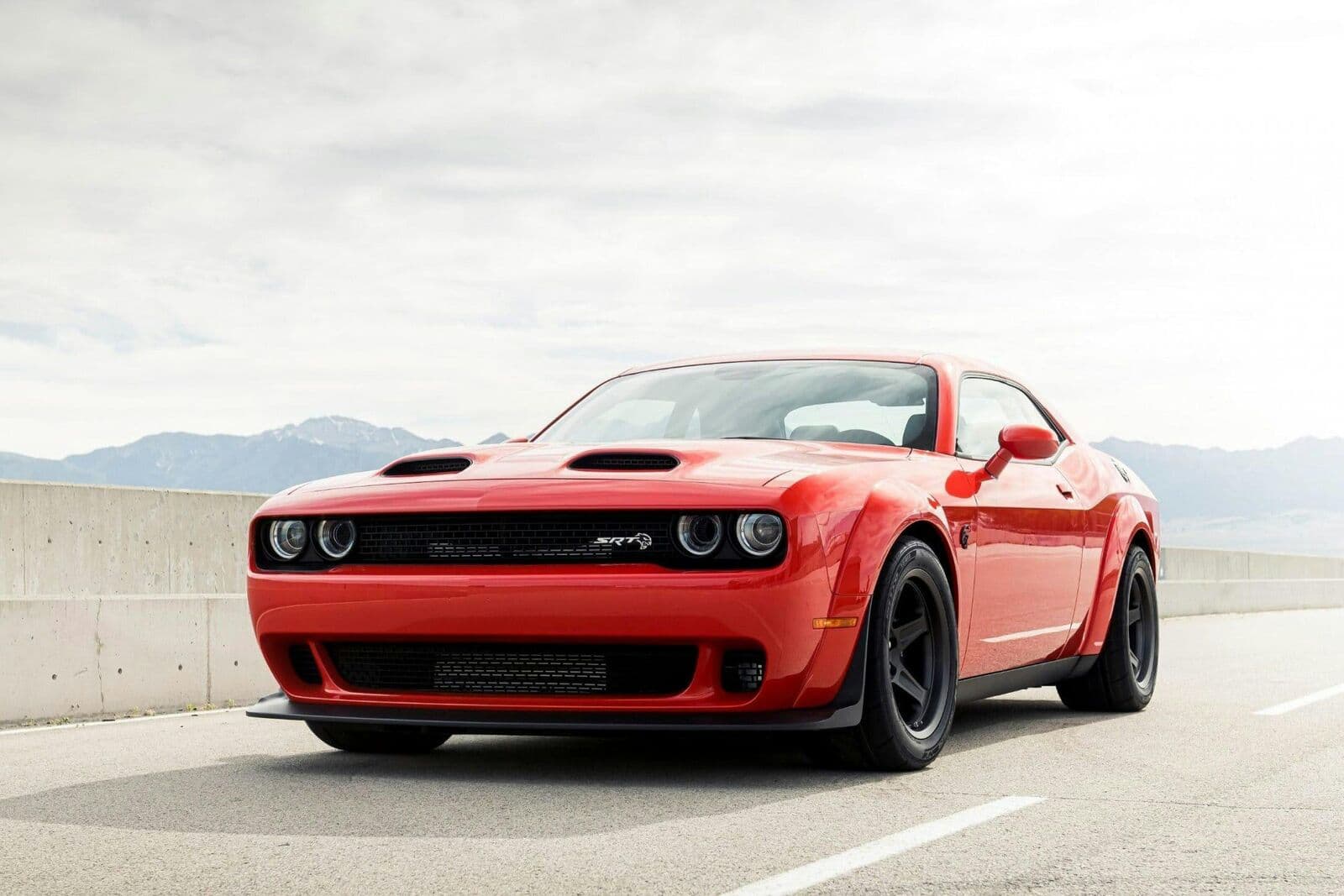 Red Dodge Challenger muscle car parked on an open road.