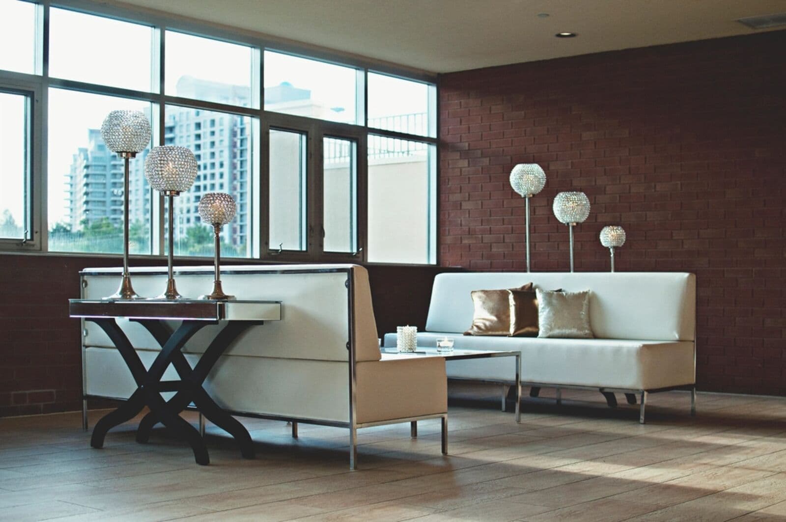 Two white sofas and a coffee table in a bright room with brick walls and large windows.